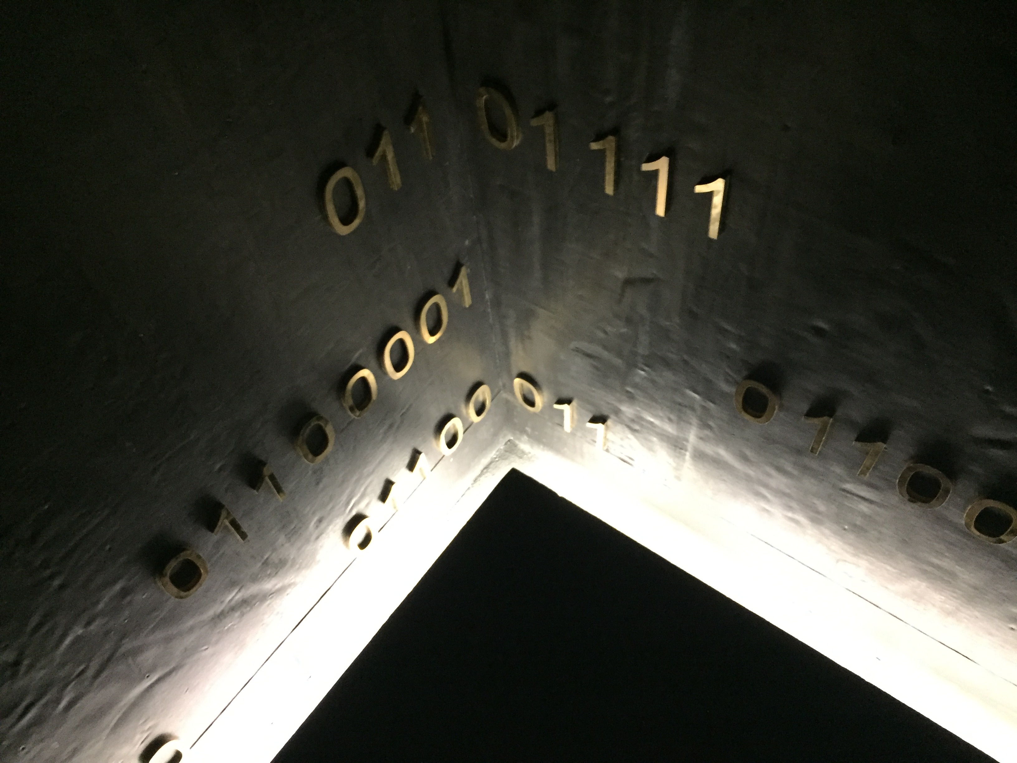 A dark corner, lit from below to reveal artistic strings of binary code